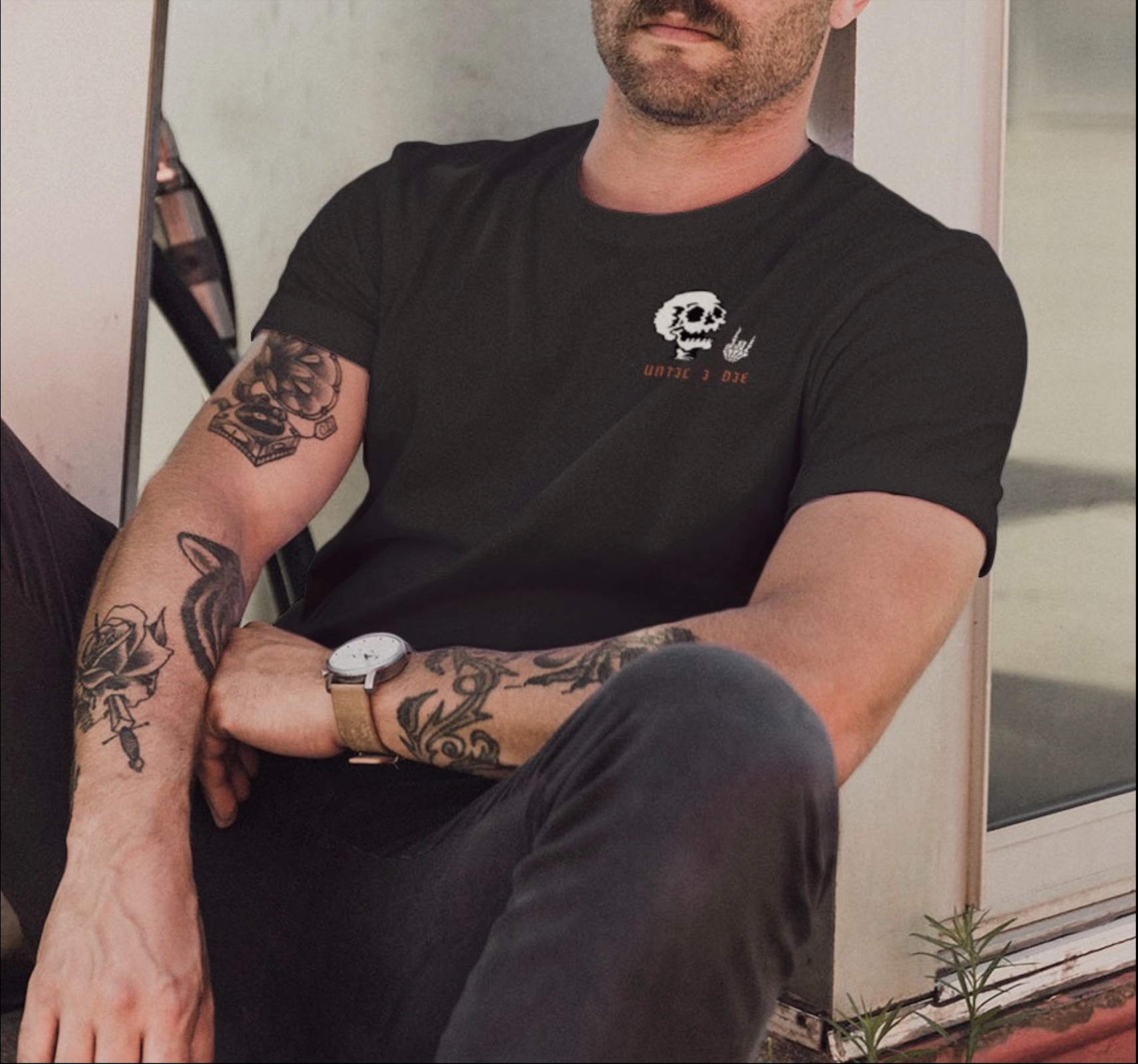 Shown, tatted man wearing black version of t-shirt design showcasing front of shirt 